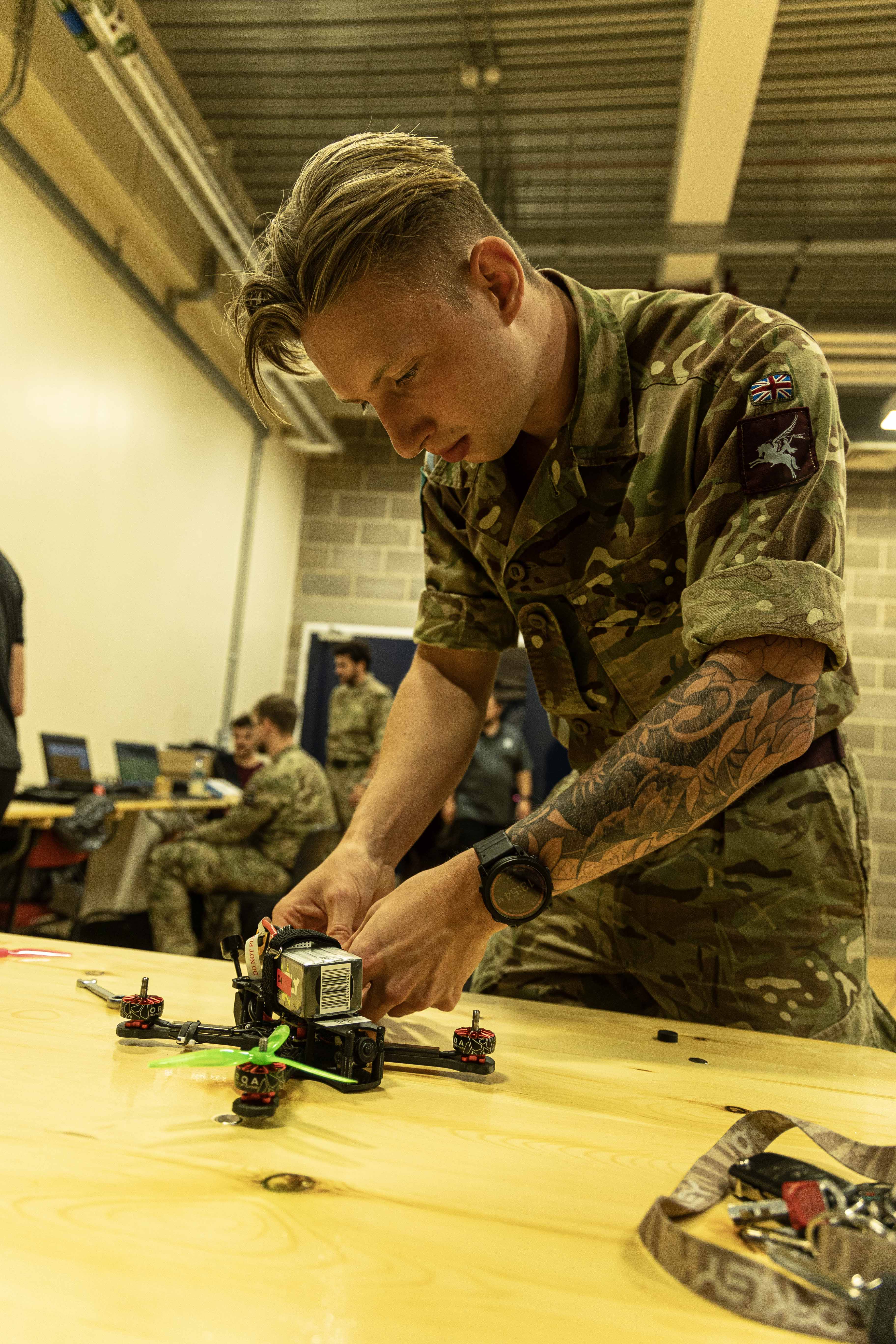 Photo: Team member standing at a workbench while performing a maintenance task on a First Person View Uncrewed Aircraft System